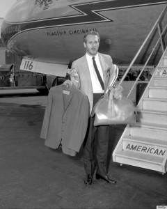 Actor Paul Newman, carrying some clothes on a hanger walks t